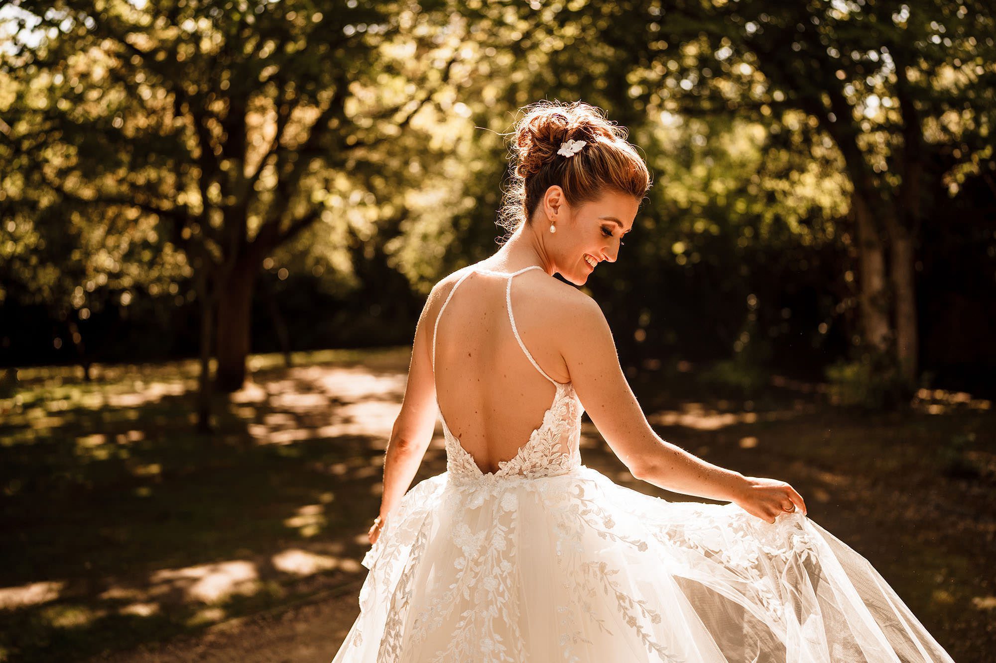 a bride in The Cotswolds countryside is admiring her wedding dress